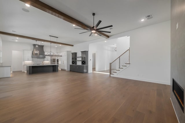 unfurnished living room featuring beam ceiling, a fireplace, ceiling fan, and dark hardwood / wood-style flooring