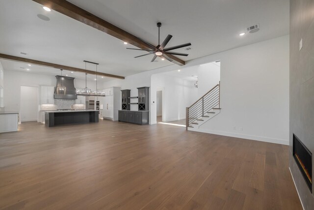 kitchen with beam ceiling, hardwood / wood-style flooring, white cabinets, hanging light fixtures, and a large island