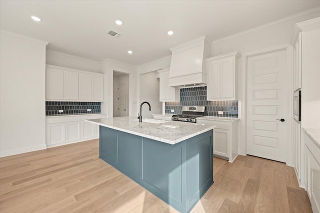 kitchen with stainless steel range oven, decorative backsplash, white cabinets, custom exhaust hood, and light wood-type flooring