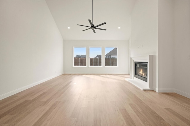 unfurnished living room with ceiling fan, light wood-type flooring, and high vaulted ceiling