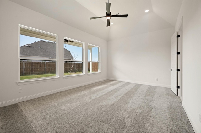 carpeted spare room featuring ceiling fan, a wealth of natural light, and vaulted ceiling