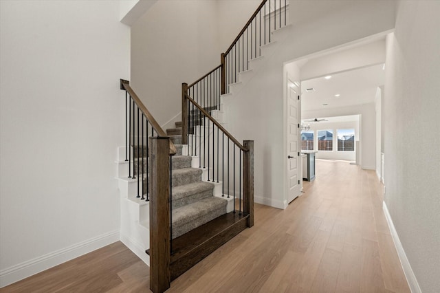 stairway featuring ceiling fan and hardwood / wood-style floors