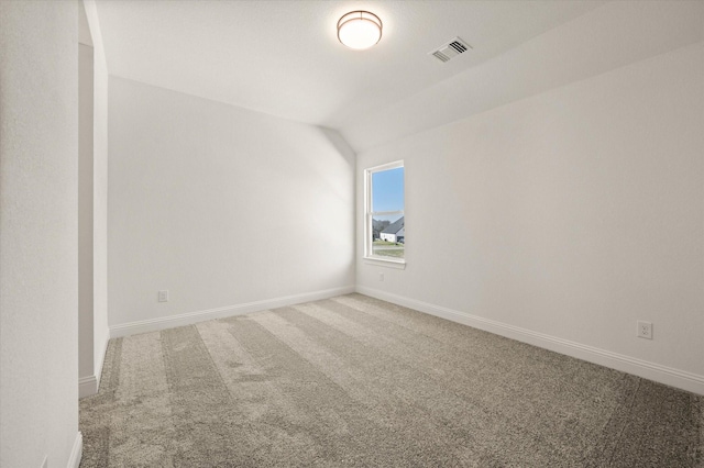 carpeted empty room featuring vaulted ceiling