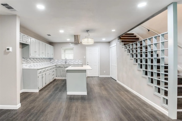 kitchen with a kitchen island, decorative light fixtures, sink, backsplash, and dark hardwood / wood-style flooring