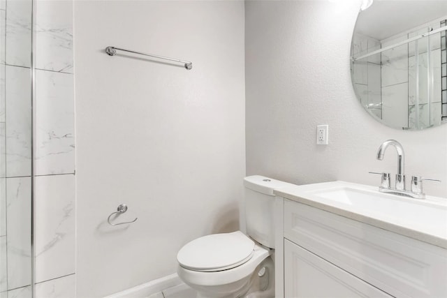 bathroom featuring tiled shower, vanity, and toilet