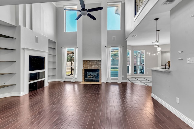 unfurnished living room with a fireplace, hardwood / wood-style floors, built in features, and a high ceiling