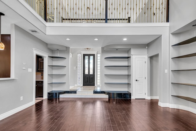 foyer entrance featuring a towering ceiling and wood-type flooring