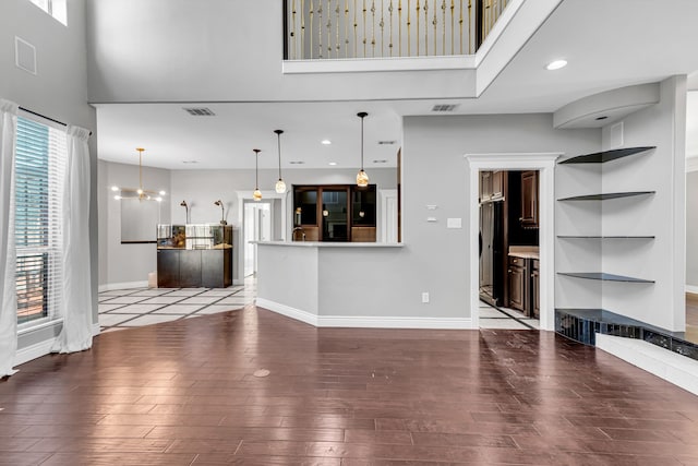 unfurnished living room with a towering ceiling, a wealth of natural light, and an inviting chandelier