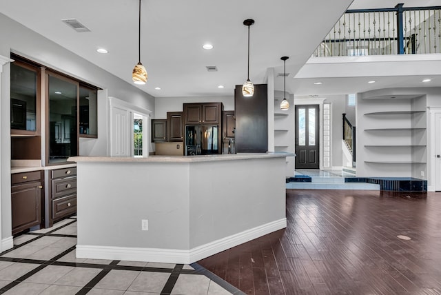 kitchen featuring a center island, black refrigerator, dark brown cabinetry, and hanging light fixtures