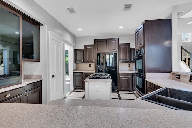 kitchen featuring black appliances, dark brown cabinetry, sink, and tasteful backsplash