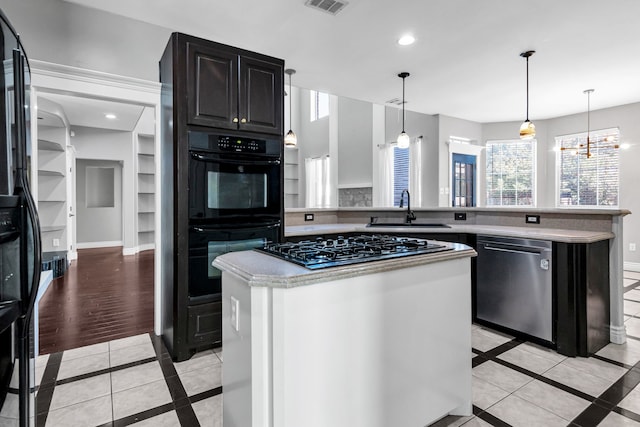 kitchen with dishwasher, sink, black double oven, gas stovetop, and a kitchen island