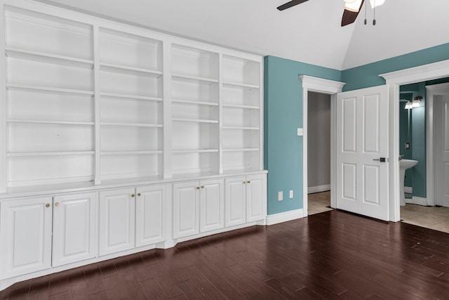 unfurnished bedroom featuring ceiling fan, dark wood-type flooring, connected bathroom, and vaulted ceiling