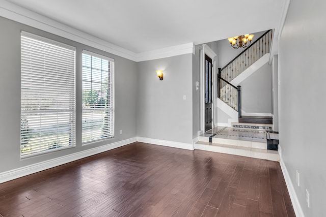 empty room with hardwood / wood-style floors, an inviting chandelier, and ornamental molding