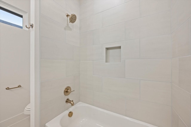 bathroom with tiled shower / bath combo and toilet