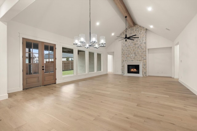 unfurnished living room with french doors, a large fireplace, ceiling fan with notable chandelier, light hardwood / wood-style flooring, and beamed ceiling