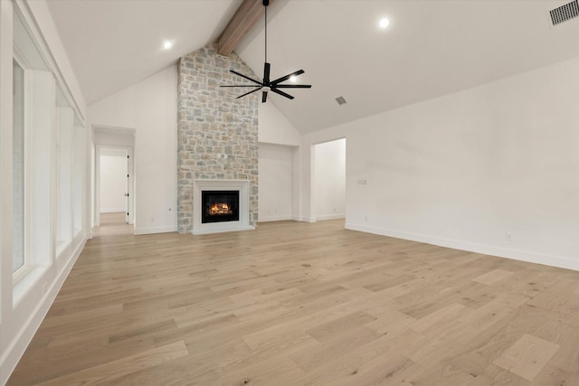 unfurnished living room with high vaulted ceiling, a stone fireplace, light hardwood / wood-style flooring, ceiling fan, and beamed ceiling