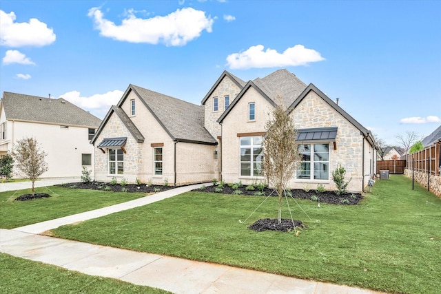 french country inspired facade featuring central air condition unit and a front yard