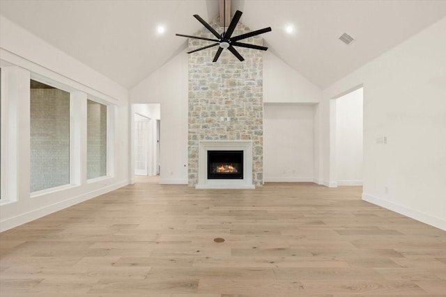 unfurnished living room with a stone fireplace, ceiling fan, light hardwood / wood-style floors, and vaulted ceiling with beams