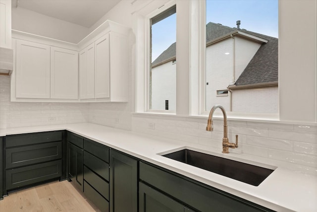 kitchen featuring white cabinets, light hardwood / wood-style floors, plenty of natural light, and sink