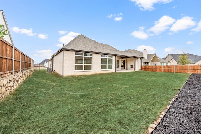 rear view of property featuring cooling unit and a lawn