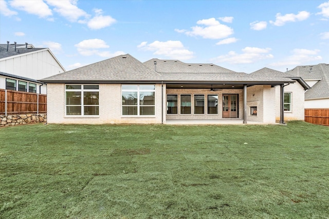 rear view of house with ceiling fan, a patio area, and a lawn