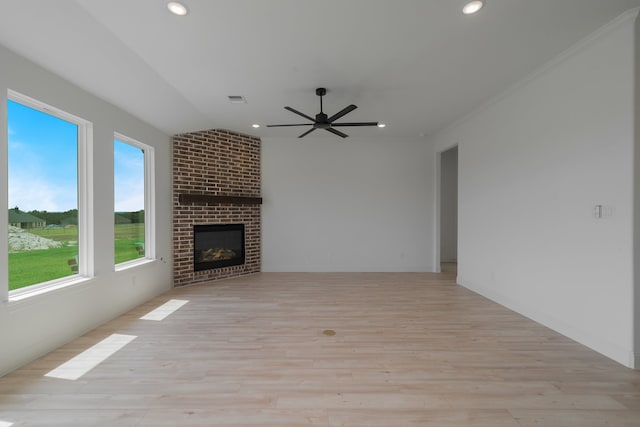 unfurnished living room with ceiling fan, light wood-type flooring, crown molding, and a brick fireplace