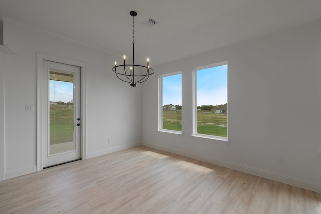 unfurnished dining area featuring an inviting chandelier and light wood-type flooring