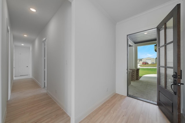 corridor with ornamental molding and light hardwood / wood-style floors