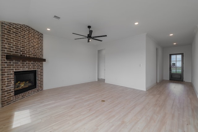 unfurnished living room featuring crown molding, a brick fireplace, ceiling fan, and light hardwood / wood-style flooring