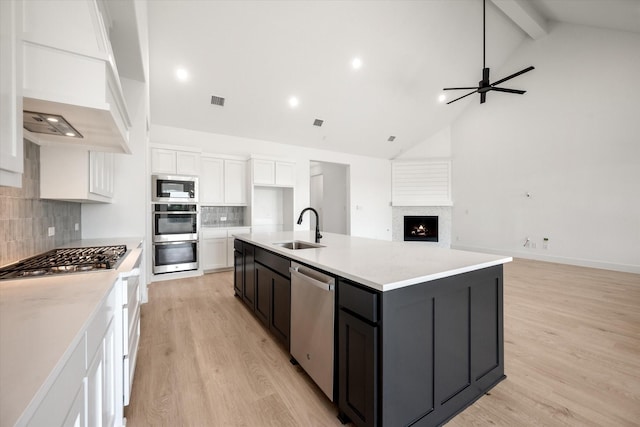 kitchen with sink, a kitchen island with sink, stainless steel appliances, light hardwood / wood-style floors, and white cabinets