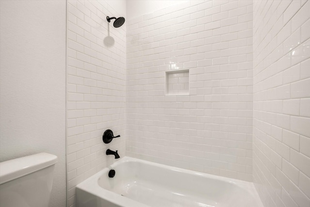 bathroom with toilet and tiled shower / bath