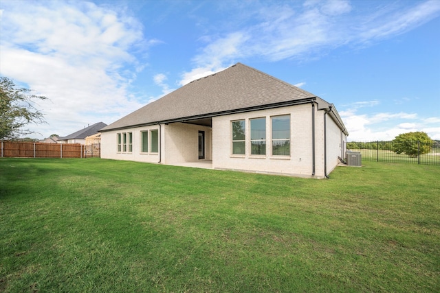 rear view of property with central AC unit and a lawn