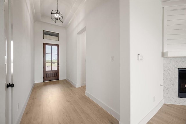 entrance foyer featuring a tile fireplace, light hardwood / wood-style flooring, and a notable chandelier