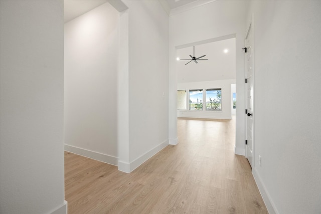 hall with a towering ceiling and light hardwood / wood-style flooring