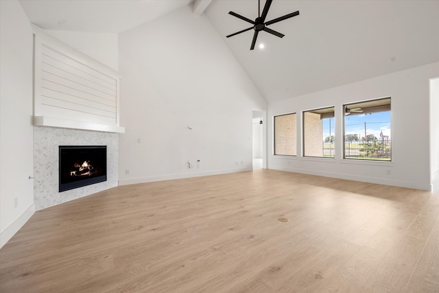 unfurnished living room featuring high vaulted ceiling, a tiled fireplace, beam ceiling, ceiling fan, and light wood-type flooring