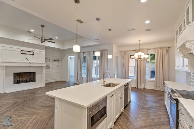 kitchen with dark parquet floors, sink, white cabinets, a kitchen island with sink, and stainless steel appliances