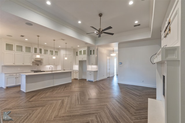 unfurnished living room featuring dark parquet flooring, sink, crown molding, a raised ceiling, and ceiling fan