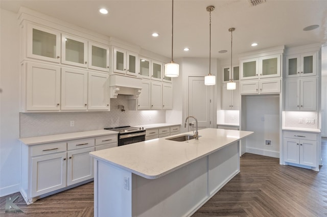 kitchen featuring sink, stainless steel range with electric stovetop, dark parquet floors, an island with sink, and white cabinets