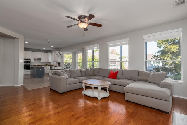 living room featuring dark wood-type flooring and ceiling fan with notable chandelier