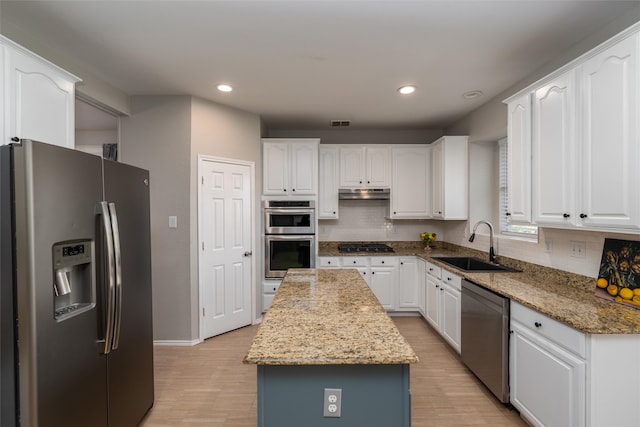 kitchen featuring a center island, stone counters, white cabinets, sink, and appliances with stainless steel finishes