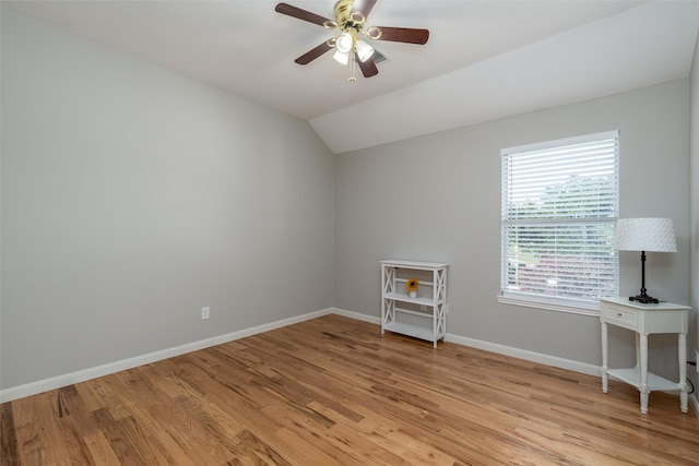 spare room with light wood-type flooring, vaulted ceiling, and ceiling fan