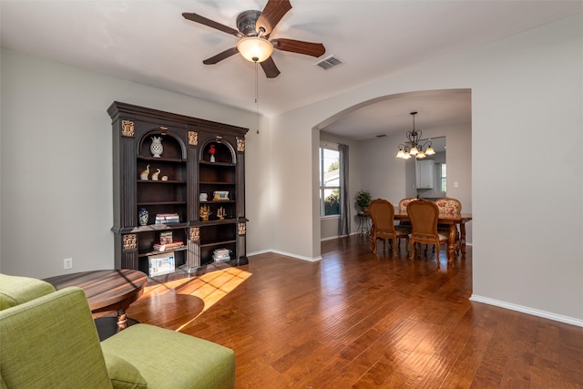 living room featuring ceiling fan with notable chandelier and dark hardwood / wood-style flooring