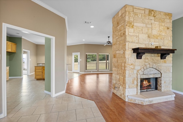 unfurnished living room featuring a stone fireplace, ceiling fan, light hardwood / wood-style floors, and ornamental molding