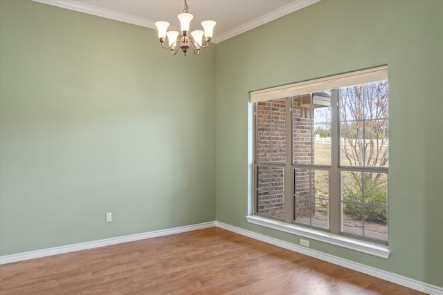 spare room featuring hardwood / wood-style flooring, crown molding, a healthy amount of sunlight, and a notable chandelier