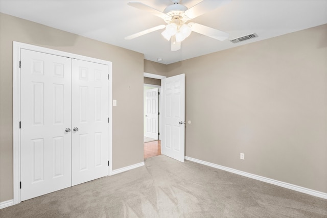 unfurnished bedroom with light carpet, a closet, and ceiling fan