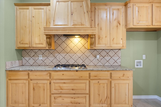 kitchen with backsplash, light stone countertops, custom range hood, and stainless steel gas stovetop