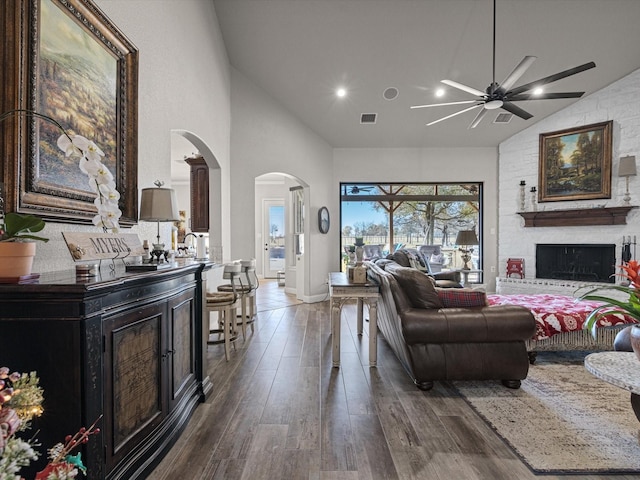 living room with ceiling fan, a fireplace, dark wood-type flooring, and vaulted ceiling