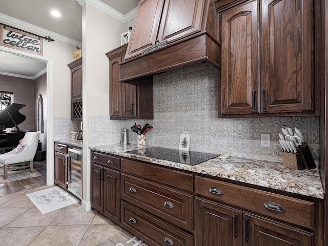 kitchen with dark brown cabinetry, light stone counters, beverage cooler, and ornamental molding