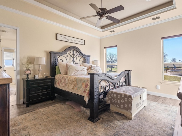 bedroom with hardwood / wood-style floors, ceiling fan, a raised ceiling, and crown molding