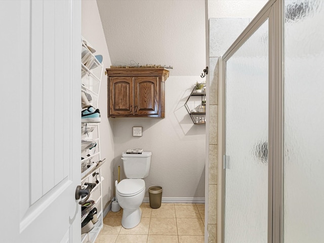 bathroom featuring tile patterned flooring, a shower with door, and toilet